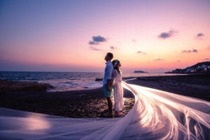 湘南の夕焼けに染まる空とビーチで前撮りするふたり