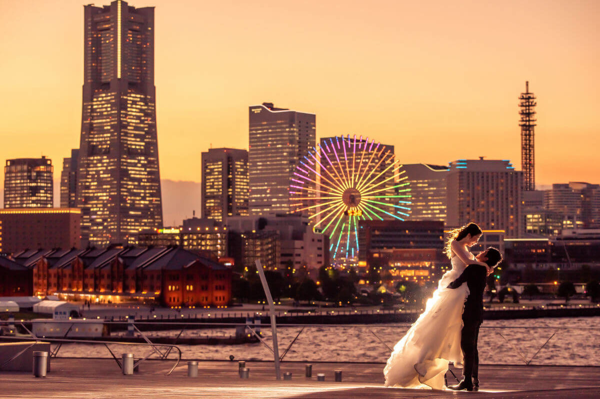 大さん橋で夕焼けをバックに新婦を持ち上げる新郎