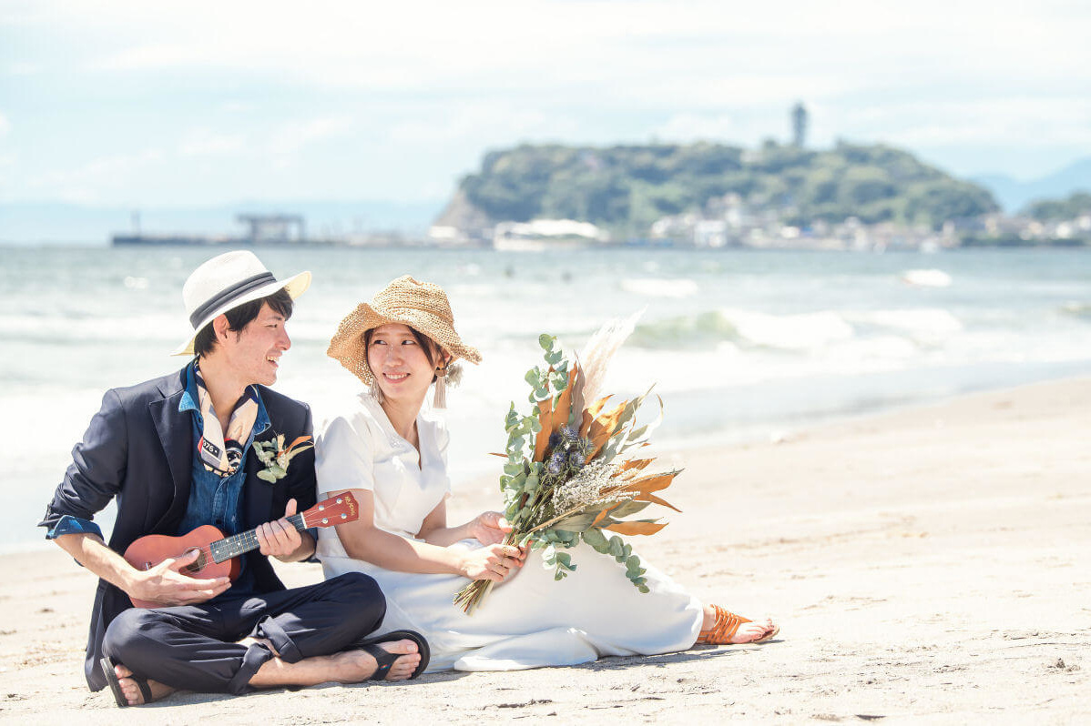湘南海岸の砂浜に座る新郎と新婦