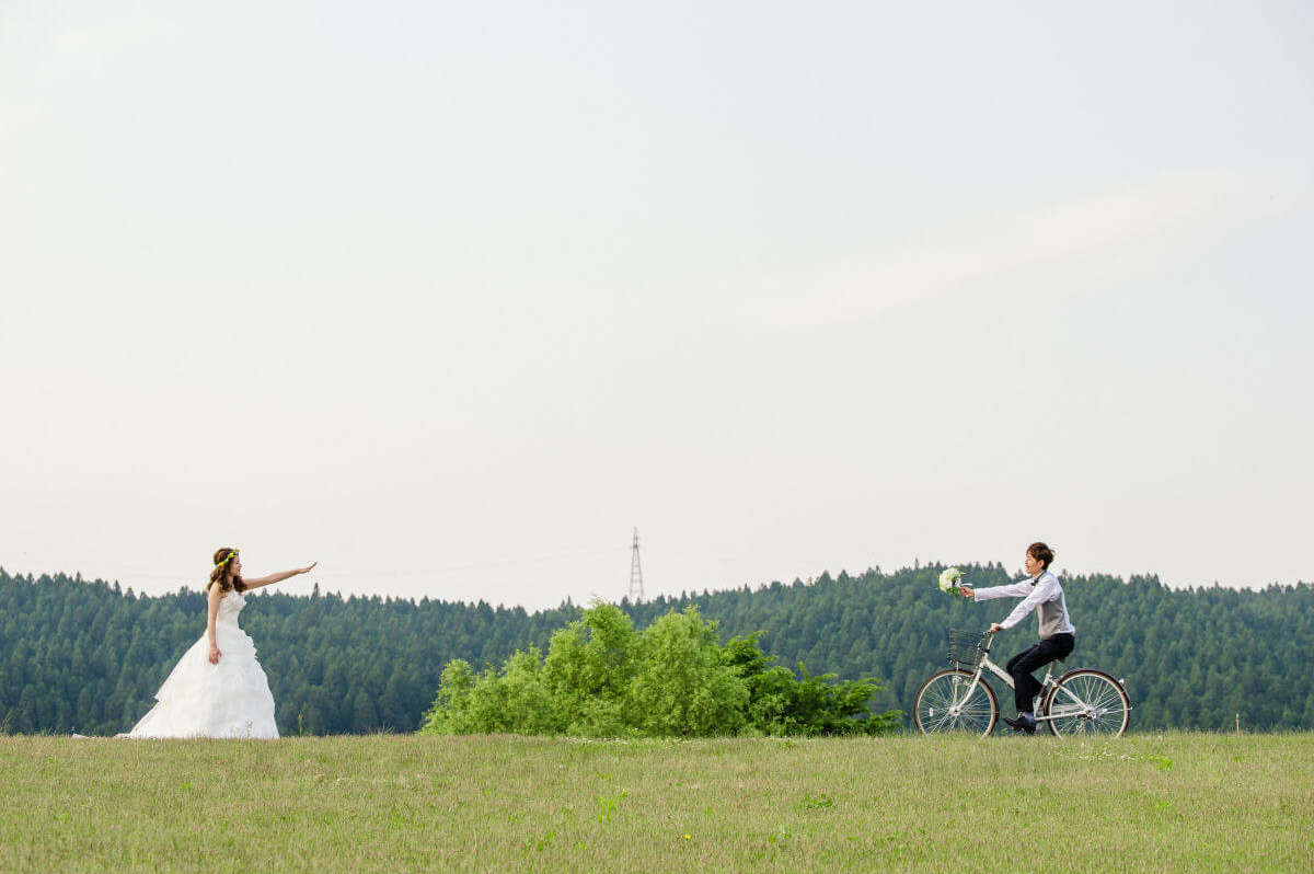 自転車に乗って新婦にブーケを渡す新郎