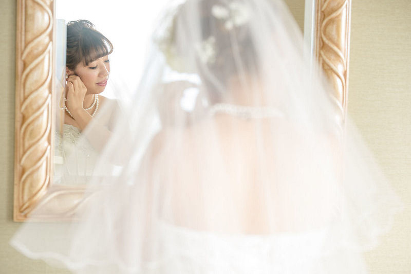 鏡の前でイヤリングをつける新婦