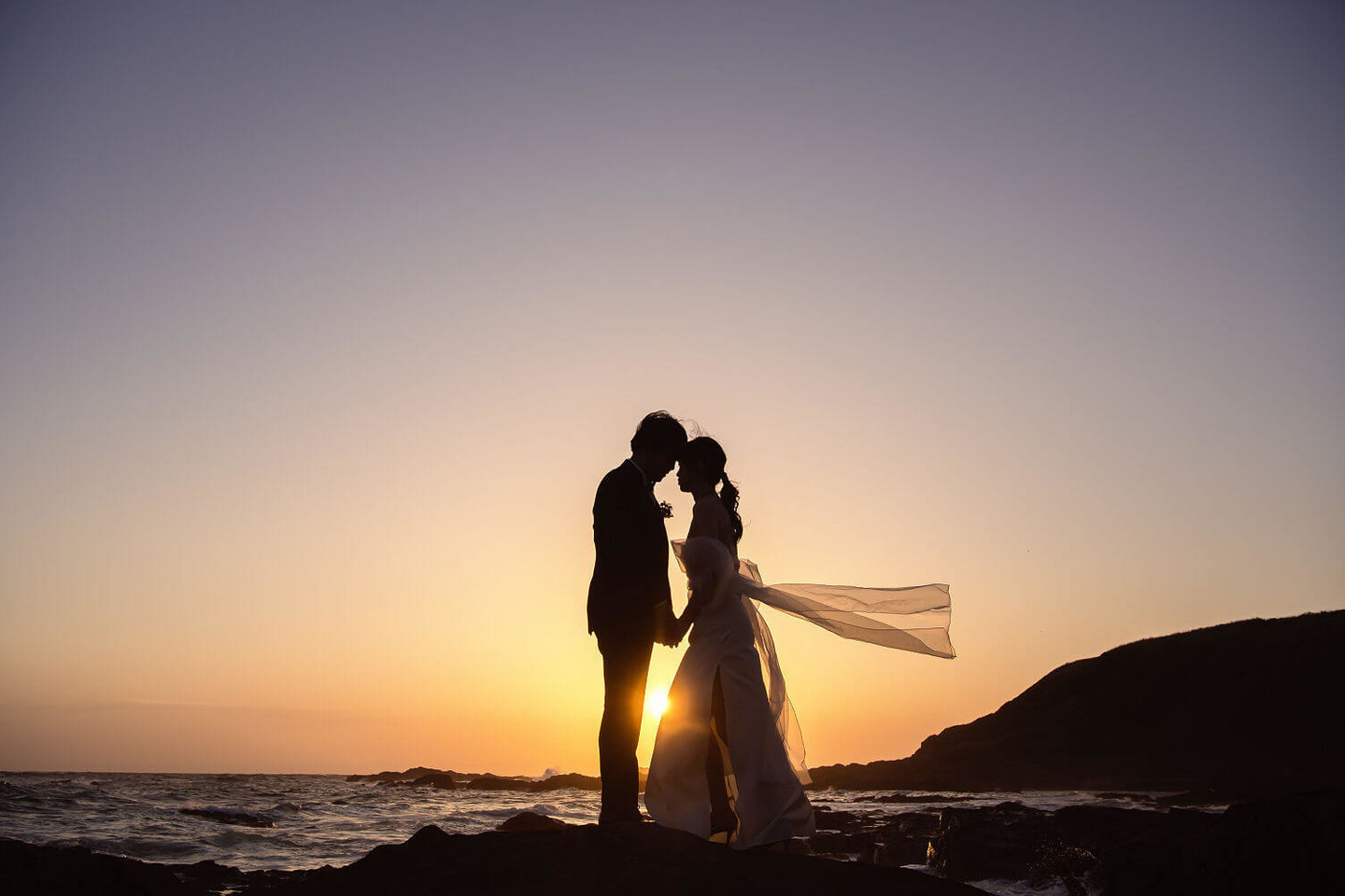 ロマンチックな夕焼けと見つめ合う新郎新婦