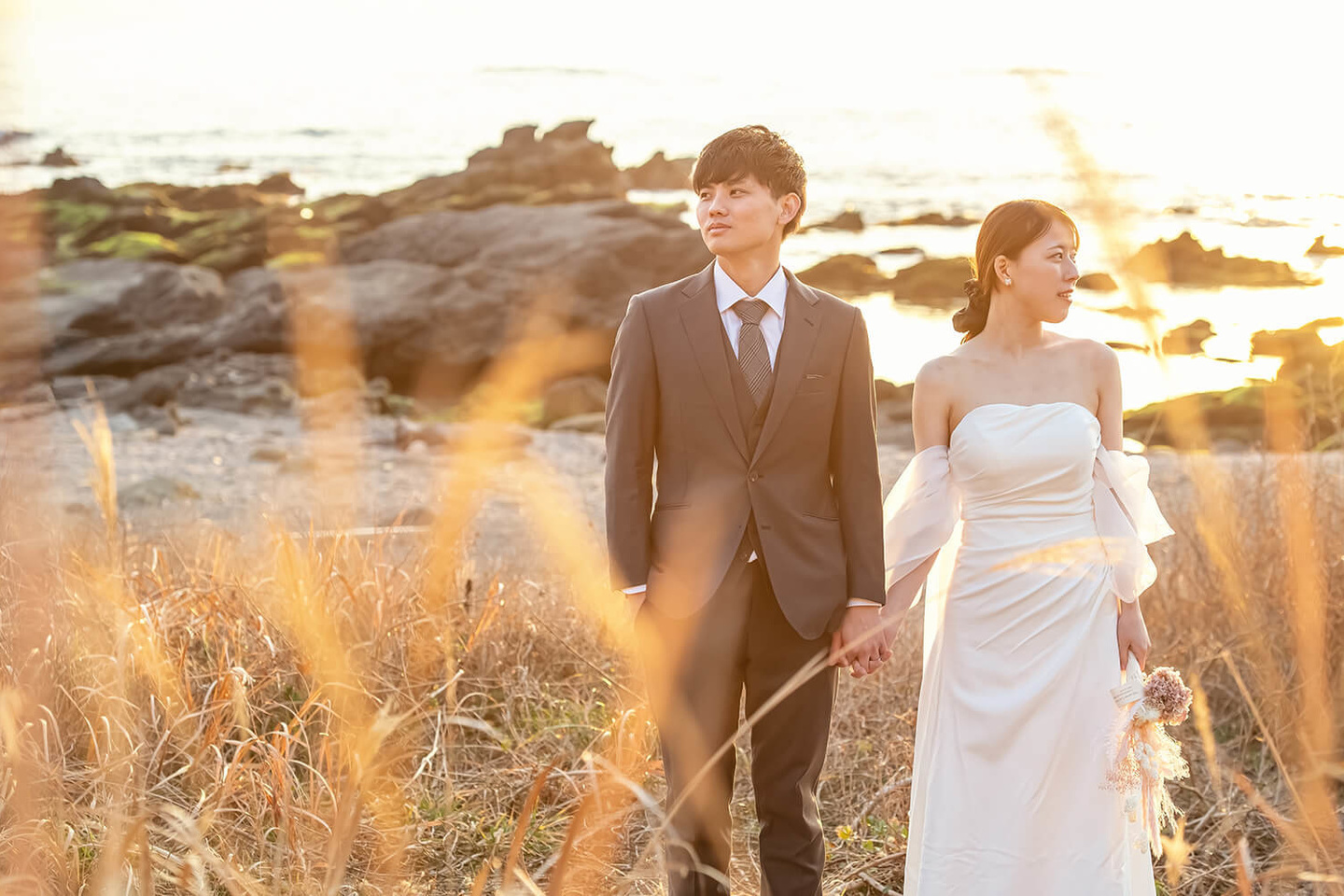 海をバックに手を繋ぐ男女