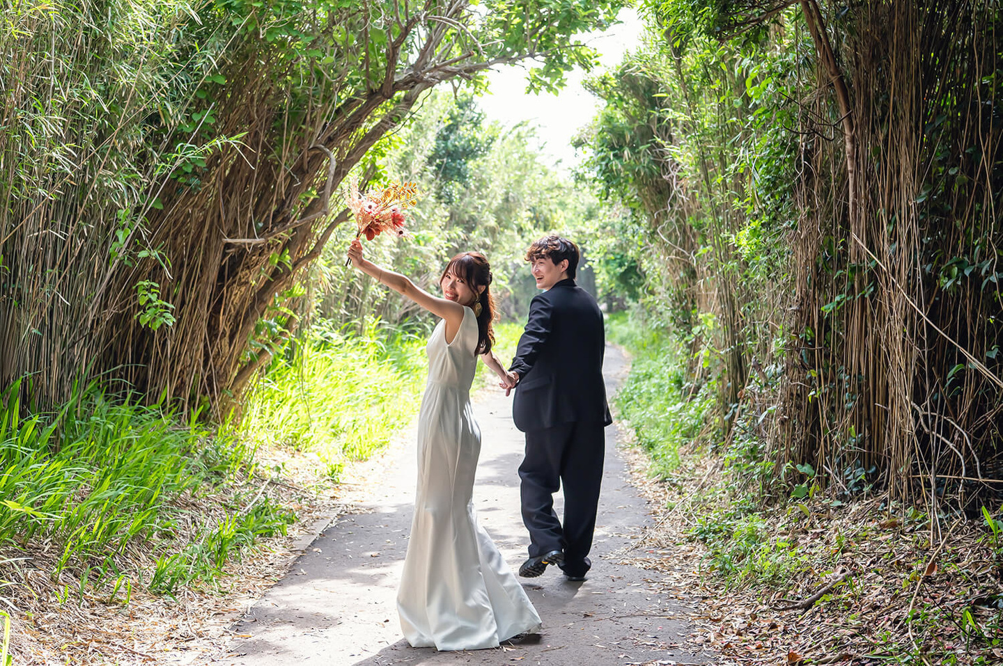 海に向かう途中でブーケを上げて歩く新婦