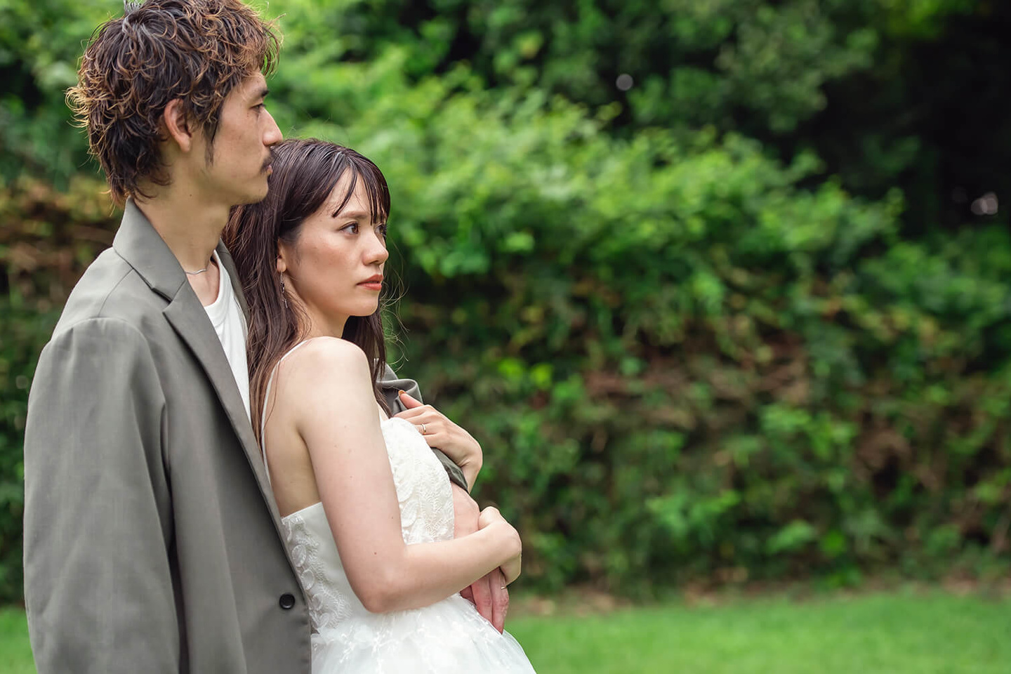自然な緑の中で新郎に寄りかかる新婦
